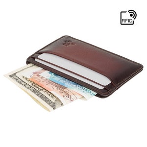 May include: A brown leather wallet with RFID blocking technology. The wallet has a card slot and is shown with cash inside.