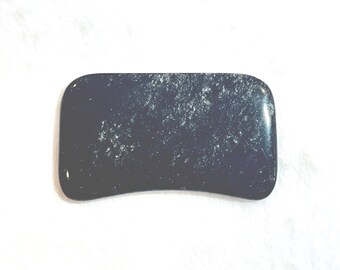 May include: A dark blue, rectangular gua sha tool with rounded edges. The stone has a smooth, polished surface with white speckling. The tool is designed for facial massage and skincare routines.