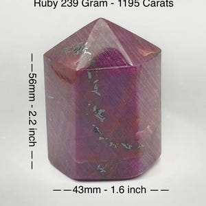 May include: A faceted ruby crystal, 2.2 inches tall and 1.6 inches wide, weighing 239 grams. The deep red gemstone has inclusions and the text "Ruby 239 Gram - 1195 Carats".