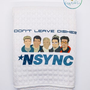 May include: White kitchen towel with a blue and white graphic of the boy band *NSYNC. The text "Don't Leave Dishes" is above the band members.