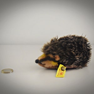 Puede incluir: Un erizo de peluche marrón y beige con una etiqueta amarilla que dice "Steiff" y "Made in Germany".
