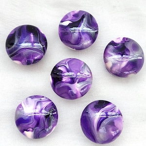 May include: Five circular buttons featuring a marbled pattern of deep purple, white, and black swirls. Each button has a smooth, glossy finish with a rounded surface, displaying a unique blend of colors that create a fluid, abstract appearance.