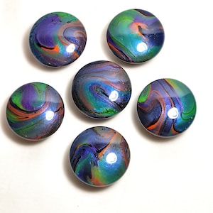 May include: A set of six circular cabinet knobs featuring a glossy, multi-colored swirl pattern. The surface of each knob displays a blend of purple, green, blue, and orange hues in a fluid, marbled design with a reflective, smooth finish.