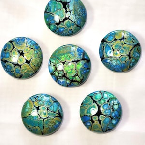 May include: Five circular cabochons featuring an acrylic pour pattern with a vibrant color palette of turquoise, lime green, and metallic gold, separated by thin black web-like veins. Each piece has a smooth, glossy, and reflective surface finish.