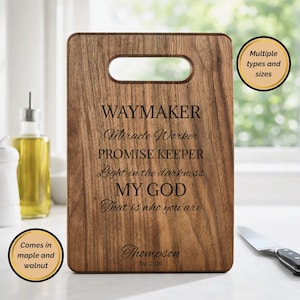 Può includere: Tagliere rettangolare in legno con un'apertura per la maniglia. La tavola presenta il testo inciso: "WAYMAKER, Miracle Worker, PROMISE KEEPER, Light in the darkness, MY GOD, That is who you are." Include il nome "Thompson" e "Est. 2026".