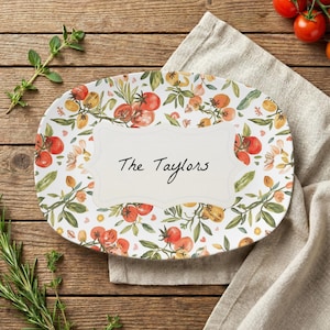 May include: Oval serving platter with a white background, adorned with a tomato and floral design. The platter features the text "The Taylors" in a decorative font, perfect for serving food at a family gathering.