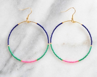 May include: A pair of gold hoop earrings with blue, green, and pink beads. The earrings are made of wire and have a simple design.