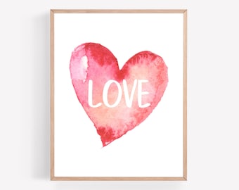 May include: A framed print with a watercolor painting of a pink heart with the word "LOVE" written in white inside the heart.