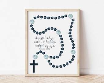 May include: A printable wall art design featuring a blue and white rosary with a black cross and the quote "Be joyful in hope, persevere in hardship, faithful in prayer. Romans 12:12".
