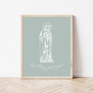 May include: A white line drawing of the Virgin Mary on a light blue background. The text "Hail Mary, full of grace" is written below the image.