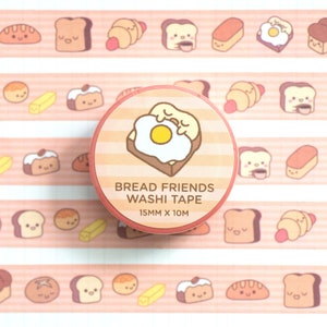 May include: A roll of pink and white striped washi tape with a cute cartoon illustration of a slice of bread with a fried egg on top. The tape is labeled "Bread Friends Washi Tape" and "15mm x 10m".