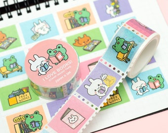 Könnte beinhalten: Zwei Rollen Washi-Tape in Rosa und Grün. Eine Rolle zeigt ein weißes Kaninchen und einen grünen Frosch, die Bücher lesen. Die andere Rolle zeigt ein weißes Kaninchen, das ein Buch liest. Beide Rollen tragen den Text "I Love Books!" und "Stamp Washi Tape 25mm x 5m".