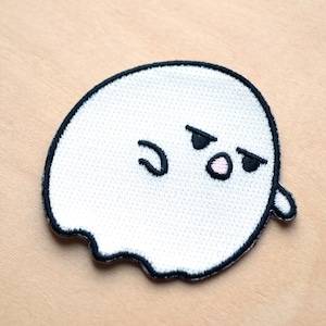 May include: White embroidered ghost patch with a black outline and a cute, grumpy expression. The ghost has black eyes and a pink nose.
