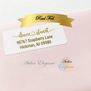May include: A white address label with gold foil text, featuring the name "diane stuart" and an address. A gold banner above reads "Real Foil." The label is on a pink envelope. The words "Atelier Elegance" are also visible.