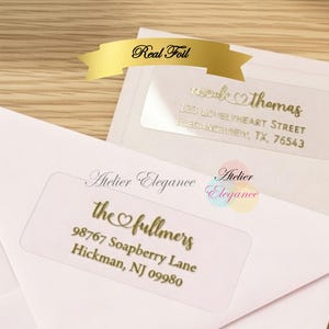 May include: Clear address labels with gold foil lettering on pink envelopes. The labels display names, addresses, and the words "Real Foil" and "Atelier Elegance". The labels are for the "fullmers" and "nicole thomas".