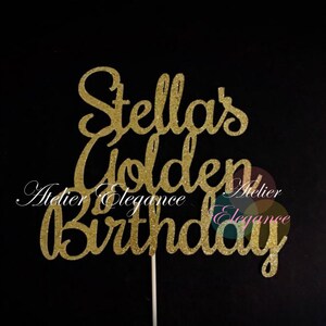 May include: A gold glitter cake topper with the words "Stella's Golden Birthday" in a cursive font. The topper is on a white stick, perfect for a birthday cake. The background is black.
