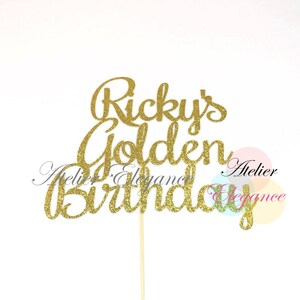 May include: A gold glitter cake topper with the words "Ricky's Golden Birthday" in a cursive font. The topper is attached to a wooden stick for easy insertion into a cake. The background is white.