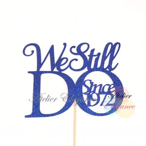 May include: Blue glitter cake topper with the text "We Still Do Since 197" for a wedding anniversary.