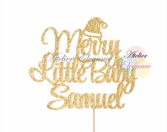 May include: Gold glitter cake topper with the text "Merry Little Baby Samuel" and a Santa hat on top.