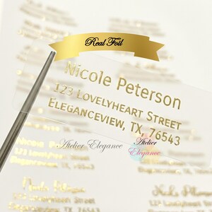 May include: Clear address labels with gold foil lettering. The labels include the name "Nicole Peterson", address, and the text "Real Foil". The labels are being held by a silver tool.