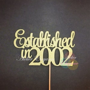 Puede incluir: Topper para pastel de purpurina dorada con el texto "Establecido en 2002".