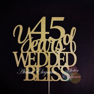 May include: Gold glitter cake topper with the text "45 years of wedded bliss".