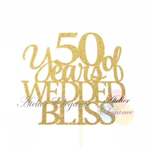 May include: Gold glitter cake topper with the text "50 Years of Wedded Bliss" and the words "Atelier Elegance" on the bottom.