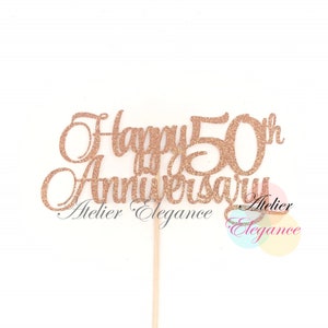 May include: Rose gold glitter cake topper with the text "Happy 50th Anniversary" and the words "Atelier Elegance" below.