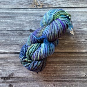May include: A skein of chunky yarn in shades of blue, green, and purple. The yarn is hand-dyed and has a unique, textured look.
