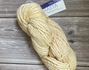 Könnte beinhalten: Ein Knäuel super dickes Garn in Elfenbein, genannt "Rasta" von der Marke "704 Ivory". Das Garn besteht aus Merinowolle und ist etwa 50 Yards (45,7 Meter) lang.