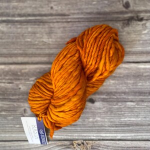 May include: A skein of orange yarn with a tag that reads "096 SUNSET" and "KAL 124".