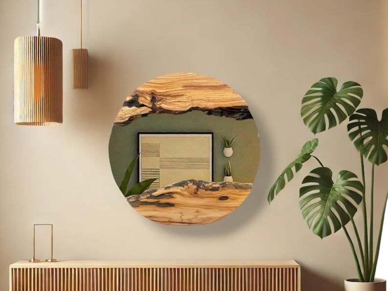 Puede incluir: Un espejo de pared circular con un marco de madera natural de borde vivo, con vetas prominentes y detalles de corteza oscura y texturizada. La superficie reflectante muestra el reflejo de una l&aacute;mina geom&eacute;trica enmarcada y dos macetas peque&ntilde;as.