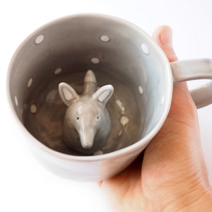 May include: A grey ceramic mug with white polka dots and a grey ceramic fox figurine inside.