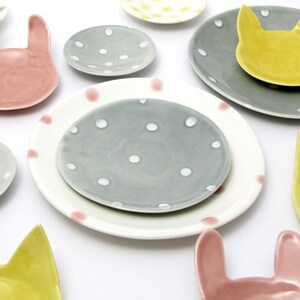 May include: A set of small ceramic dishes in various colours and patterns. The dishes feature polka dots, bunny and cat shapes.