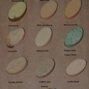 May include: A collection of 15 oval-shaped soap bars with various scents and ingredients. The soap bars are arranged in three rows of five. The soap bars are all a light beige color, with some having a darker brown or green color. The soap bars are labeled with their scents and ingredients, such as "Oatmeal, Milk and Honey Scrub", "Coconut Lemongrass with Chia", "Frankincense", "Patchouli", "Milk and Honey", "Moroccan Fig", "Lavender", "Naked Goat", "Peppermint Poppy Seed", "Vanilla Butter", "Coffee and Honey", "Joyful Goat", "Coconut Ginger Almond", "Citrus Green Tea", and "Spiced Pear".