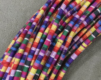 May include: A close-up of a bundle of colorful striped fabric cord. The cord is made of woven fabric and has a variety of colors, including red, orange, yellow, green, blue, purple, and pink.