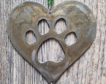 May include: A metal heart-shaped ornament with a paw print cut out. The ornament is hanging from a string of blue and green beads.