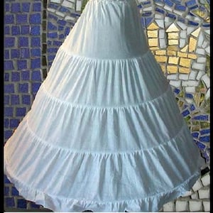 Puede incluir: Un enaguas de tul blanco con múltiples capas, creando una silueta completa y voluminosa. El enaguas está diseñado para agregar volumen y forma a una falda o vestido.