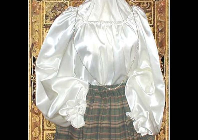 Pode incluir: Uma blusa branca de cetim com mangas compridas e bufantes e um decote franzido. A blusa &eacute; usada sobre uma saia xadrez.