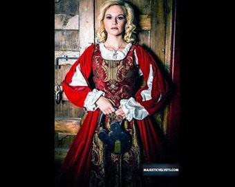 May include: A woman in a red and gold brocade dress with white lace sleeves and a red velvet cape. She is holding a large, ornate key in her hand. The background is a wooden door with a keyhole.
