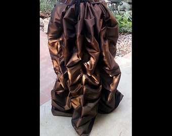 May include: A brown and gold satin skirt with a gathered, ruffled design. The skirt is long and flowing, and it would be perfect for a formal event.