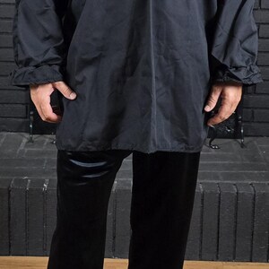 Puede incluir: Una camisa negra de manga larga con cuello en V y pantalones negros.