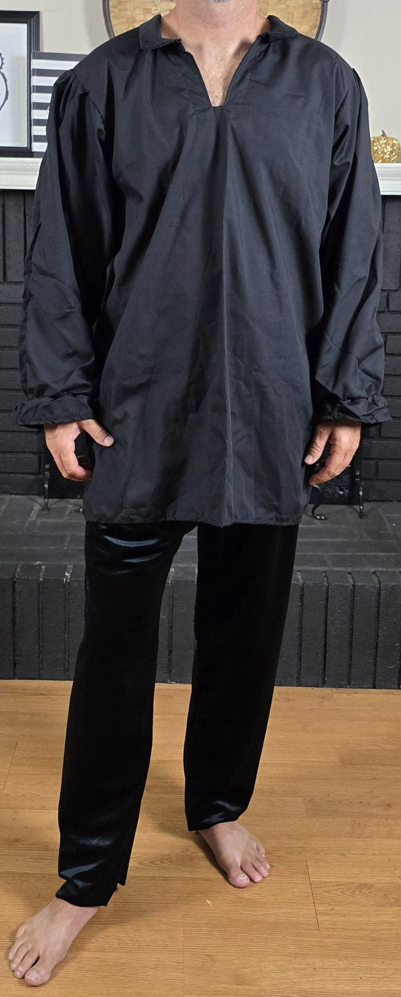 Puede incluir: Una camisa negra de manga larga con cuello en V y pantalones negros.