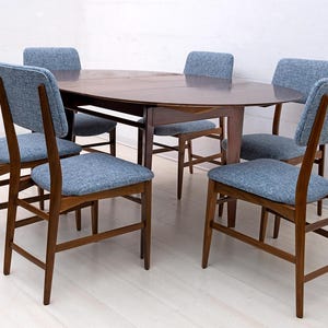 May include: A mid-century modern dining set featuring a dark wood oval table and six chairs. The chairs have blue upholstered seats and backs, with a wooden frame. The table is approximately 60 inches long.