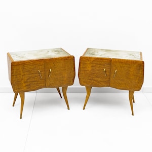 Puede incluir: Dos mesitas de noche a juego de estilo moderno de mediados de siglo. Cada una tiene una tapa estampada de color claro y un mueble de madera con dos puertas y tiradores de latón. Los armarios están sostenidos por cuatro patas anguladas.
