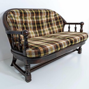 May include: A vintage loveseat with a dark wood frame and plaid upholstery in shades of brown, green, and yellow. The loveseat features a curved back, armrests, and button-tufted detailing, offering a classic and inviting aesthetic.