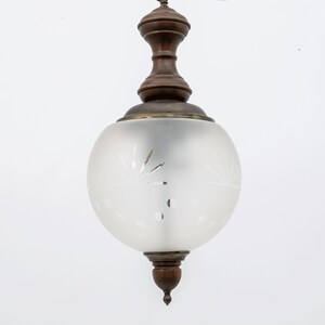 May include: A frosted glass globe pendant light fixture with a wood finial and a brass base.