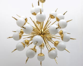 May include: A gold-toned chandelier with multiple white globe-shaped lights. The lights are arranged in a starburst pattern.