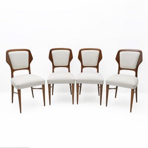 May include: Four mid-century modern chairs with a walnut-stained wood frame and white upholstered seat and back. The chairs have a distinctive curved back design and tapered legs, set against a white background.