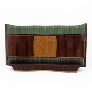 May include: A mid-century modern cabinet with a dark wood finish. The cabinet features a central carved panel and green and gold accents. It has a curved top and a lower shelf.